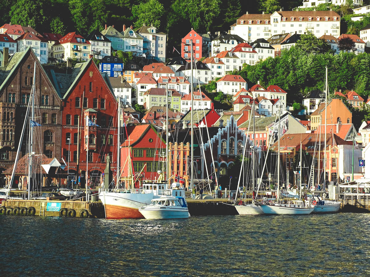 boats by the famous port of bergen, bryggen. on the steep hills next to the port beautiful and colorful houses are built.